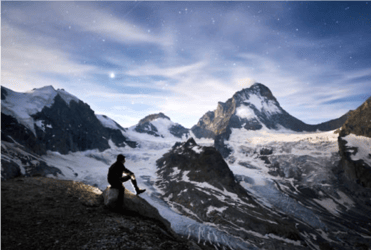 man sitting summit gazing at stars